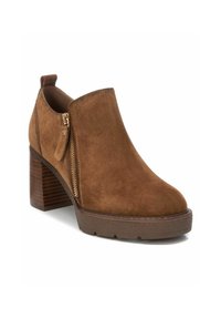 Stivale in camoscio marrone alla caviglia con punta rotonda, chiusura laterale con zip e tacco in legno impilato. Presenta una suola in gomma texture per una buona aderenza.