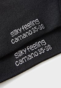 Schwarze Socken aus einem seidigen Material, mit grauem Text, der "seidiges Gefühl" und "Carmano 35-38" zeigt, der in den Stoff eingestrickt ist.