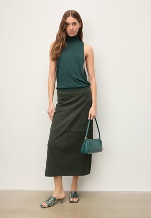 Ujjatlan sötétzöld felső magas nyakkal, olívazöld midi szoknya, kékeszöld kézitáska és mintás, sarkú papucsok. Simaságot sugárzó anyagok.