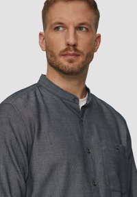 Donkergrijze button-up shirt met een mandarijnkraag, textuurstof en een borstzak, voorzien van kleine knopen en een casual pasvorm.