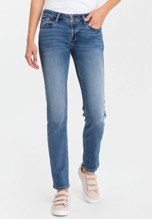 Light blue denim jeans with a straight leg cut, five pockets, and a button closure, paired with pale pink slip-on sneakers.