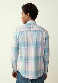 Camicia a maniche lunghe a quadri in tonalità di blu chiaro, rosa e beige. Presenta un colletto con bottoni, orlo arrotondato e polsini con bottoni.