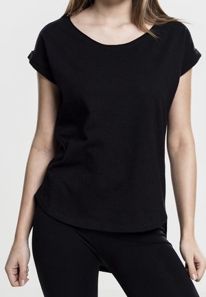 Schwarzes kurzärmeliges Oberteil aus glattem Baumwollstoff, mit rundem Ausschnitt und hochgekrempelten Ärmelsäumen, kombiniert mit schwarzen Leggings.