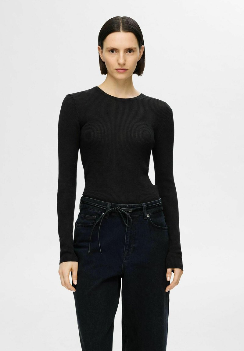 Svart ribbad långärmad topp med rund halsringning, kombinerad med högmidjade mörka jeans med dragsko i midjan och avslappnad passform.