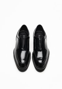 Zwarte gepolijste leren schoenen met een gestroomlijnd ontwerp, ronde neus, elastische zijkanten en een gestructureerde zwarte zool.