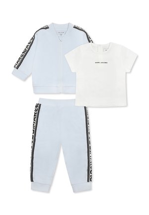Veste et pantalon de jogging bleu clair avec des rayures noires sur les côtés ; t-shirt blanc avec le texte "MARC JACOBS". Tissu doux, design décontracté.