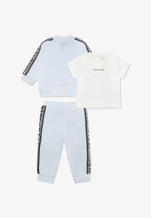 Veste et pantalon de jogging bleu clair avec des rayures noires sur les côtés ; t-shirt blanc avec le texte "MARC JACOBS". Tissu doux, design décontracté.