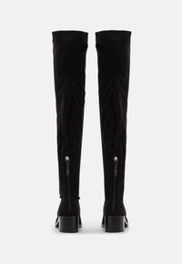 Cizme negre peste genunchi cu un finisaj din suede neted, toc pătrat și fermoare laterale pentru o purtare ușoară. Design minimalist fără accente suplimentare.