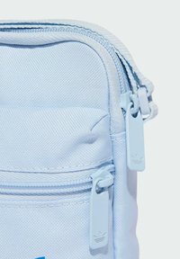 Borsa in tessuto azzurro chiaro con superficie testurizzata, dotata di due cursori coordinati con accenti logo e una tasca frontale.