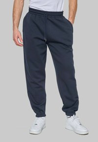 Pantalons de surv êtement bleu marine en tissu doux, avec une taille élastique dotée de cordons de serrage et des poignets fuselés au niveau de la cheville.