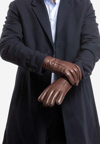 Brown leather gloves with a smooth texture, featuring four fingers and detailed stitching, worn by a person in a dark coat.