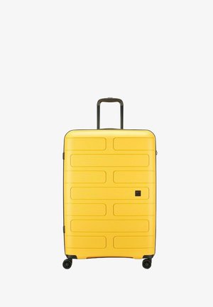 Valise rigide jaune avec un design strié, texture lisse, double roulettes et une poignée rétractable pour une maniabilité aisée.