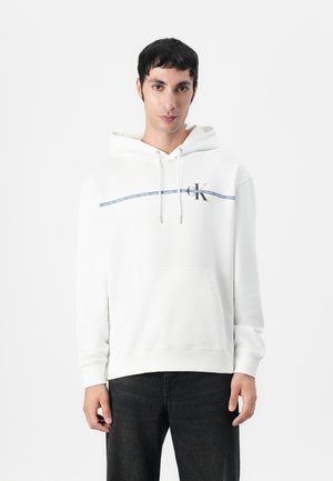 Witte hoodie met een trekkoord, een voorzak en het CK-logo op de linkerborst. Heeft een marineblauwe streep en een zachte, gestructureerde stof.