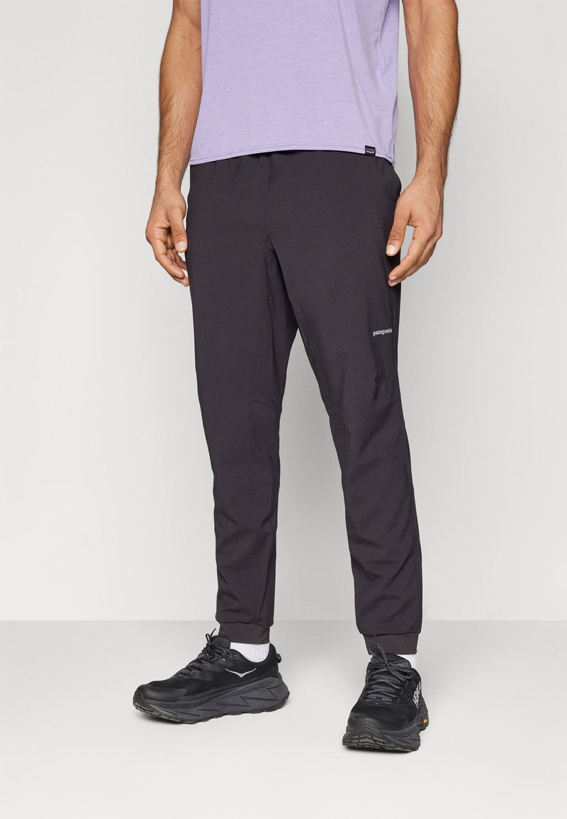 Zwarte lichtgewichte broek met elastische tailleband en taps toelopende pijpen. Voorzien van een zijzak en een reflecterend logo op de onderzijde van het linkerpijp.