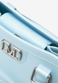 Sac à main bleu clair en matériau laqué brillant, avec quincaillerie en argent et une plaque logo. Bandoulières doubles et design minimaliste.