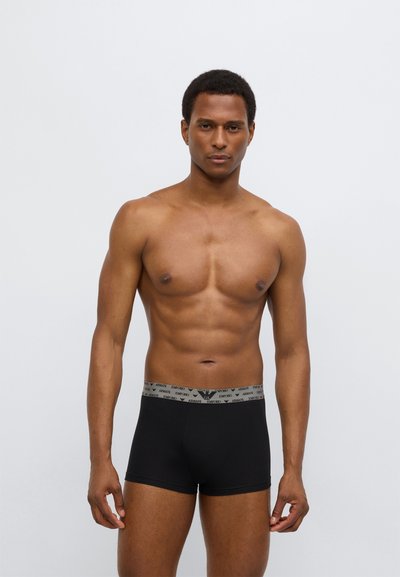 Schwarze Boxershorts mit grauem elastischem Bund, der mehrfaches Logo-Textmuster aufweist. Glatte Textur und figurbetontes Design.