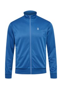 Blå zip-up jacka i mjukt material, med hög krage, sidofickor och en diskret vit logotyp på bröstet.
