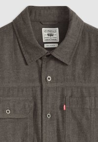Grijze vissengraat shirt met een button-down kraag, twee borstzakken en een merklabel. Voorzien van zilverkleurige knopen met een zwart ontwerp.