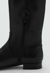 Czarne skórzane botki do kolan z bocznym zamkiem błyskawicznym, zaokrąglonym noskiem i niskim obcasem blokowym. Gładka tekstura z subtelnymi detalami przeszyć.
