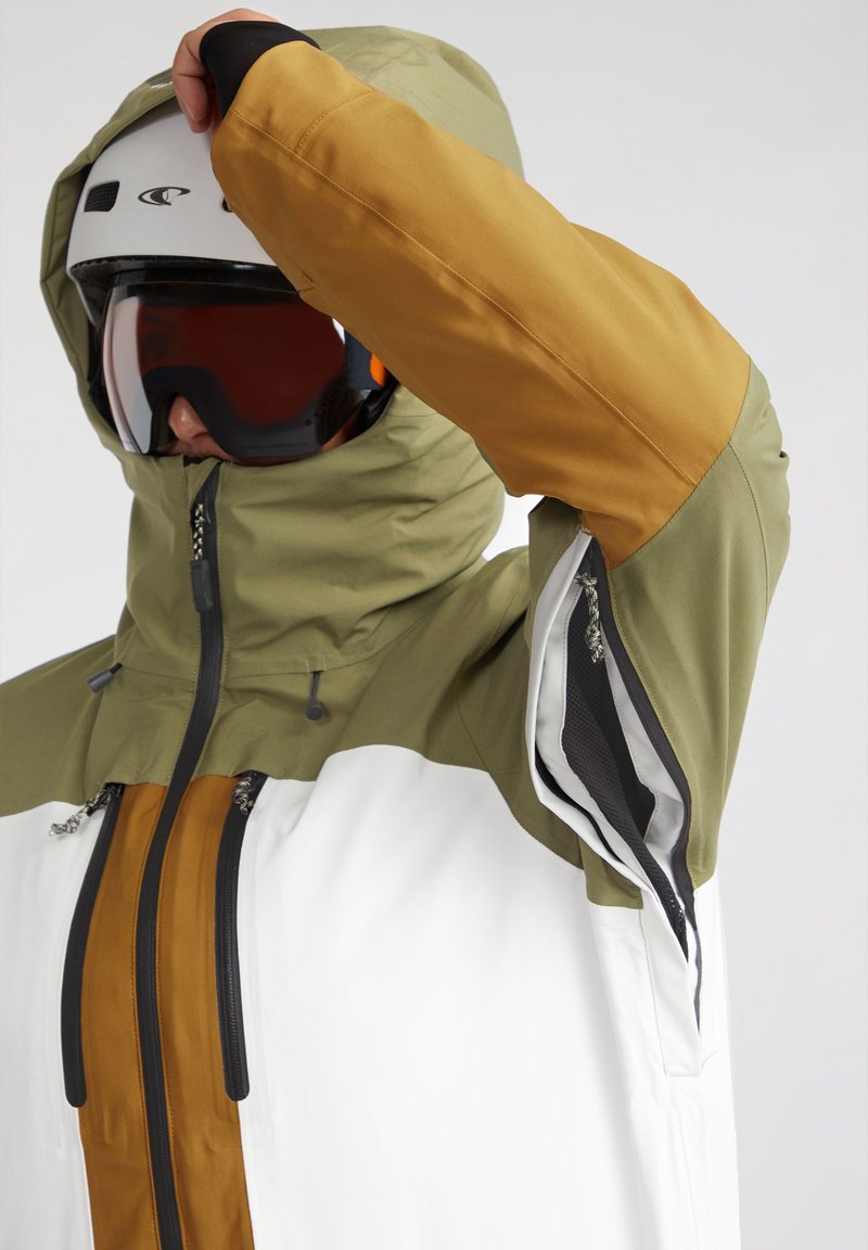 Skijacke mit einer grünen Kapuze und gelb-braunen Ärmeln, weißem Körper, Frontreißverschluss und Belüftungsreißverschlüssen an den Seiten.