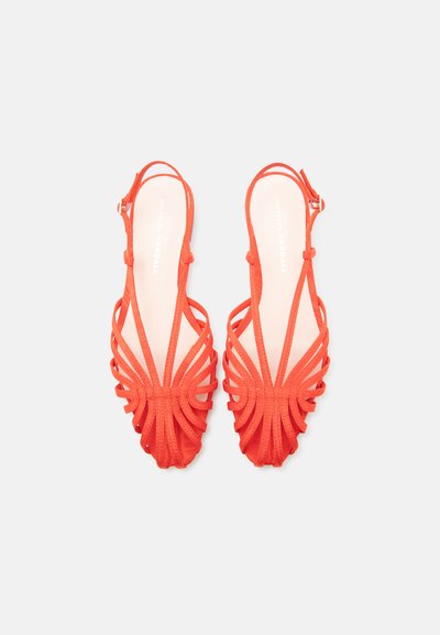 Ζευγάρι κόκκινων σανδαλιών με λουράκια πίσω, ανοιχτά δάχτυλα και σχεδιασμό με βρόχους σε λευκό φόντο.