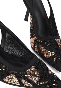 Zwarte slingbackhakken met puntige neus, versierd met roségouden en zwarte pailletten in een geometrisch patroon.