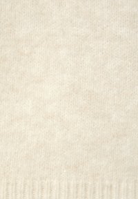 Beiger Strickstoff mit einer weichen Textur, der einen gerippten Rand aufweist. Die Oberfläche zeigt subtile Farbvariationen.