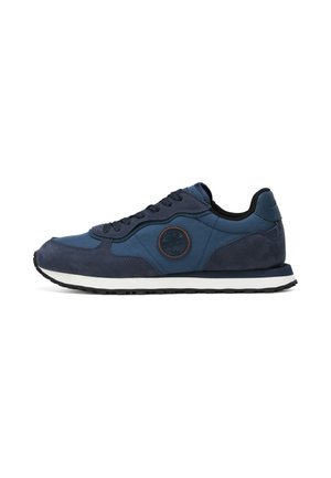 Granatowy sportowy sneaker z czarnymi sznurowadłami, białą podeszwą środkową, fakturowaną podeszwą zewnętrzną i okrągłym logo marki na bocznej części buta.
