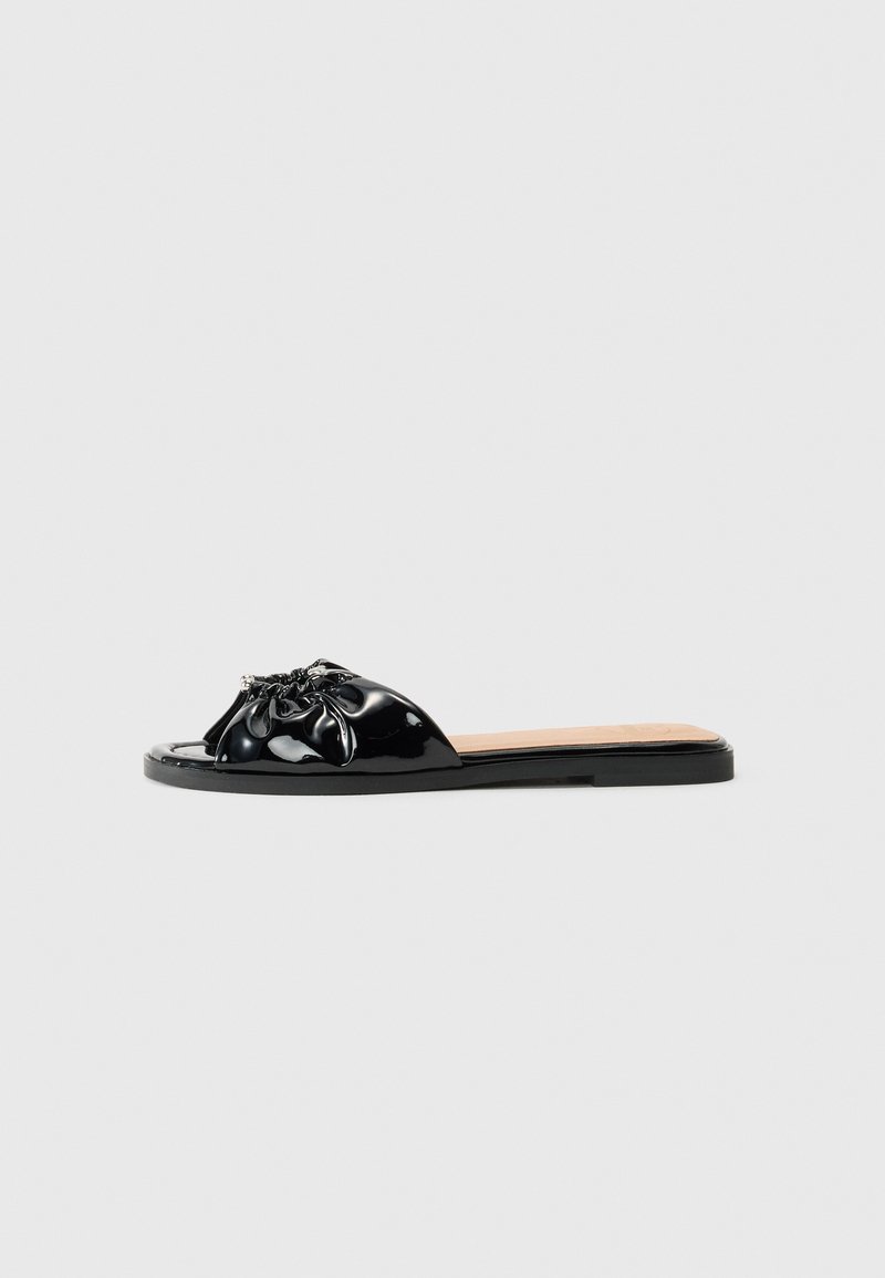 Sandal slides em patente negra com parte superior franzida, apresentando um detalhe texturizado e uma sola plana. Design simples com acentos mínimos.