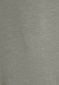 Světle šedá žebrovaná látka s vertikálními pruhy, která má jemnou a hladkou texturu. Elastická, vhodná pro různé oděvní aplikace.