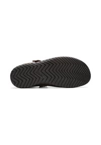 Suela de zapato de goma negra con patrón de zigzag y marca embellecida. Forma ligeramente curvada con una superficie texturizada para mejorar el agarre.