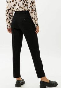 Zwarte op maat gemaakte broek met een slim fit, voorzien van een gladde textuur, subtiele achterzakken en een tailleband met lussen voor een riem.