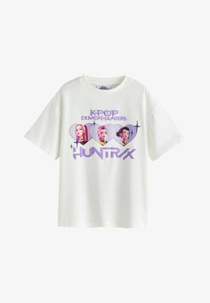 White T-shirt with purple text "KPOP DEMON HUNTERS HUNTR/X" and three female characters inside heart shapes across the chest.