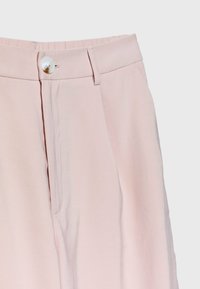 Pantalon rose clair avec une ceinture plate, des plis à l'avant et une fermeture à un seul bouton. Confectionné dans un tissu doux et lisse avec des poches latérales.