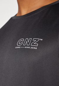 Čierne športové tričko s textúrovanou látkou. Na prednej strane má biele logo "CNZ" a text "CORE NINE.ZERO". Okrúhly výstrih, krátke rukávy.
