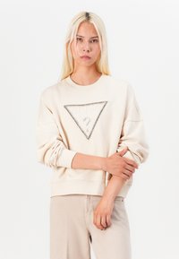 Felpa beige con un grande motivo triangolare adornato da strass argentati e testo. Presenta polsini a costine e una vestibilità rilassata.
