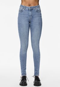 Ljusblåa skinny jeans i denimtyg har en klassisk femficksdesign och en dragkedja med knäppning. Svarta plattformsskor fulländar looken.