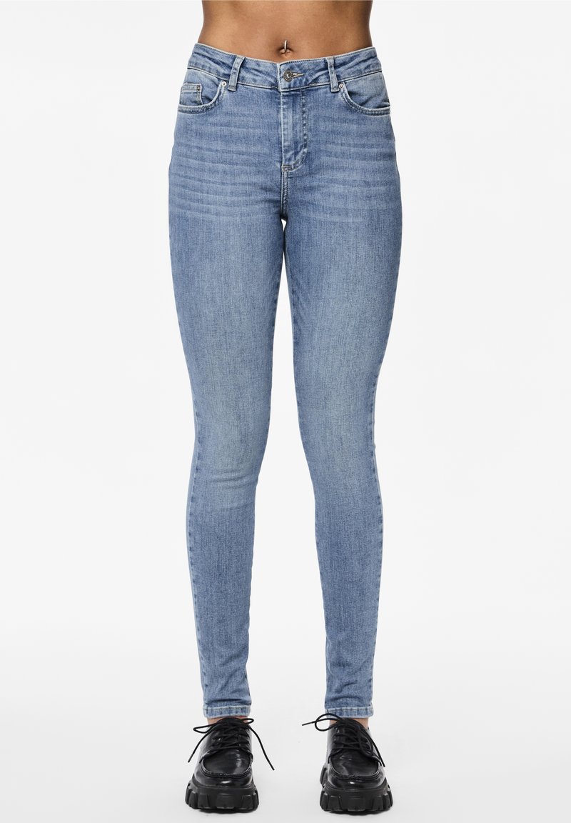 Ljusblåa skinny jeans i denimtyg har en klassisk femficksdesign och en dragkedja med knäppning. Svarta plattformsskor fulländar looken.