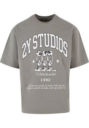 Pelēks pārāk liels T-krekls, izgatavots no kokvilnas, ar grafisku druku, kurā attēlotas trīs figūras, kas tur globusus, uzraksts "2Y STUDIOS" un gads "1992" zem tā.