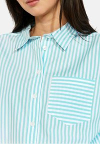 Hele sinine ja valge triibuline kraega särk, nööpidega ja rinnataskuga, millel on horisontaalsed triibud. Puuvillasegu materjal, sile tekstuur.