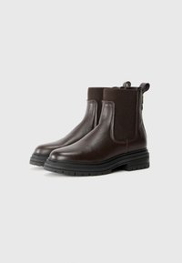 Bruine leren Chelsea-boots hebben elastische zijpanelen, een stevige zool en een treklus. De textuur is gepebbeld met een gladde afwerking.