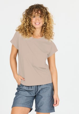 Chemise beige à manches courtes avec un col rond ; associée à un short en denim bleu avec des ourlets roulés et des poches avant.