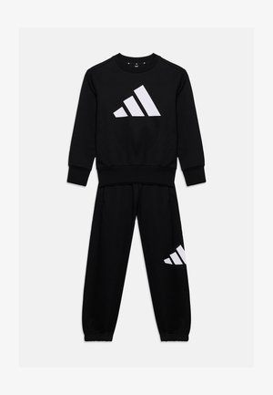 Ensemble noir composé d’un sweat-shirt à manches longues et d’un pantalon avec le logo blanc Adidas sur la poitrine et la jambe gauche, posé à plat sur fond blanc.