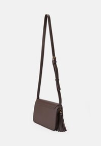 Brun lærcrossbody-veske med en frynseaccent, flat form, justerbar stropp og et rent, minimalistisk design uten synlig maskinvare.