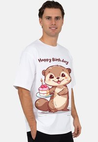 Wit T-shirt met een cartoonotter die een verjaardagstaart vasthoudt met roze glazuur en kersen, met de tekst "Happy Birthday" erboven.