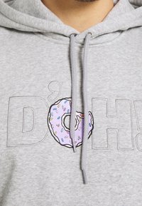 Grå huvtröja med ordet "D'OH" och en donutgrafik, omgiven av svart med en lila donut och ett flerfärgat strösselmönster.