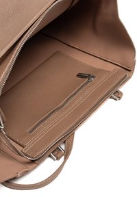 Wnętrze brązowej skórzanej torby z zamykaną kieszenią, teksturowaną powierzchnią i przestronną główną komorą. Widoczne detale z metalowym zamkiem błyskawicznym.