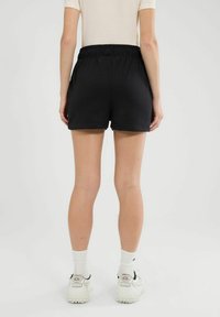 Pantalones cortos deportivos negros con una cinturilla elástica, que cuentan con dos bolsillos laterales, un ajuste relajado y una textura de tela suave.