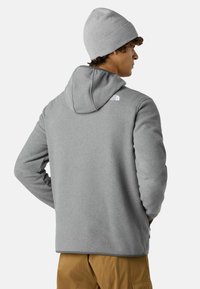 Szara polarowa kurtka z kapturem, z logo na ramieniu, w zestawie z dopasowaną czapką. Gładka faktura, swobodny kroj.