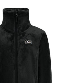 Zwarte fleecejack met hoge kraag, volledige rits en logopatch op de linkerborst. Zachte textuur en effen kleur, zonder patronen of accenten.